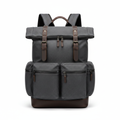 Charcoal waxed canvas roll-top men's travel backpack with leather trim on white background